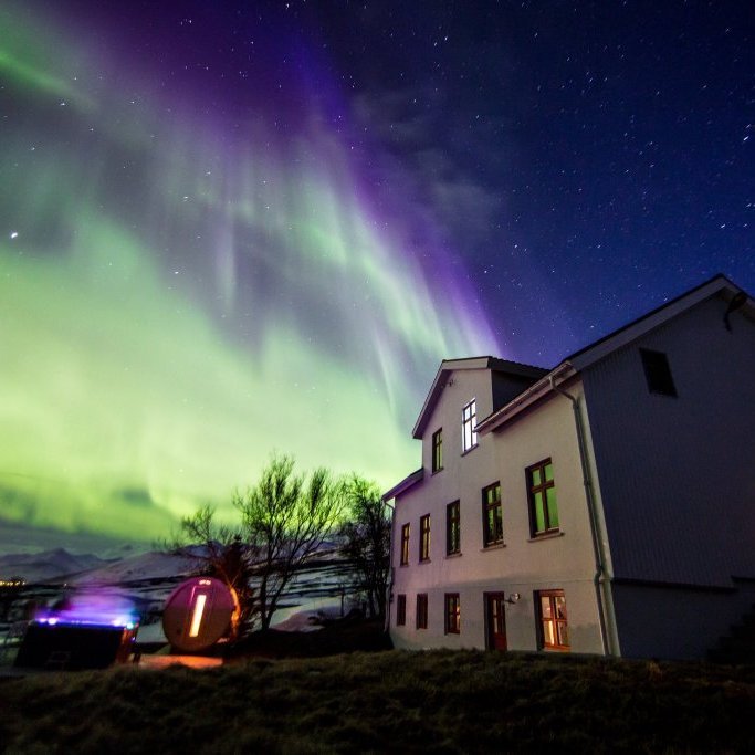 Enjoy the Northern Lights on full display while soaking in the hot tub outside Karlsá Lodge